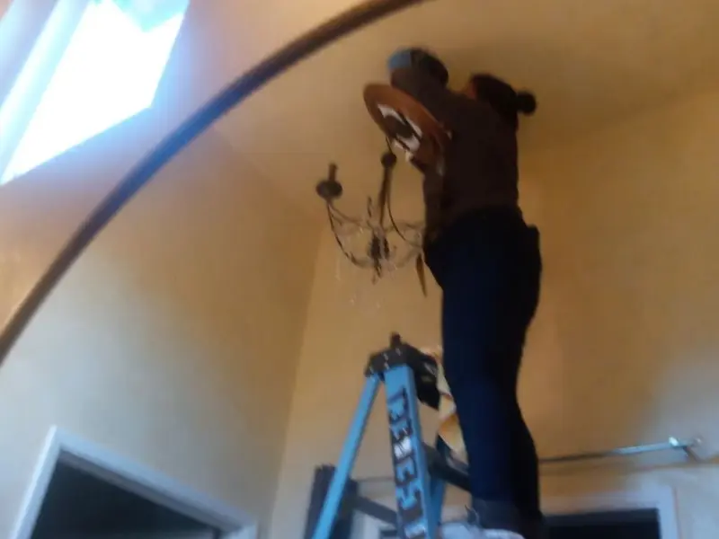 Electrician installing a chandelier in a Sebastian residence